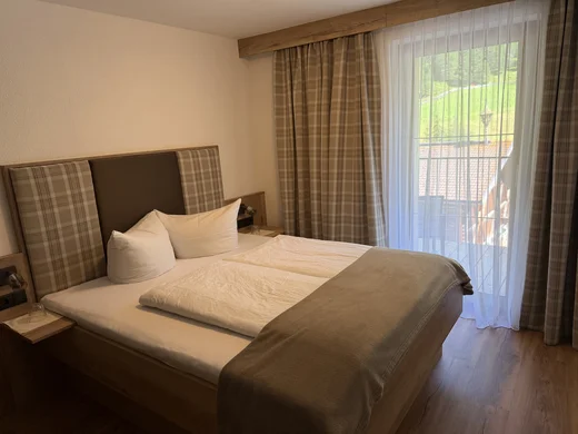 Weisskugel: your accommodation in Tyrol Cozy double bed with plaid headboard and balcony window