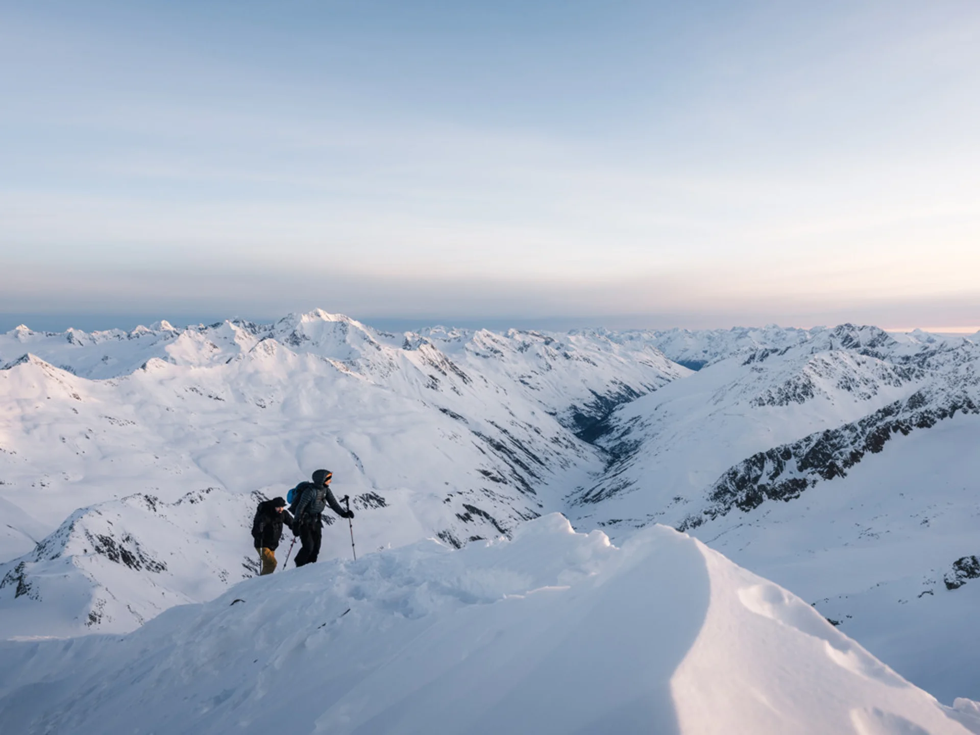 Weisskugel: your accommodation in Tyrol Zwei Wanderer besteigen schneebedeckten Berg mit Alpenpanorama bei Sonnenuntergang