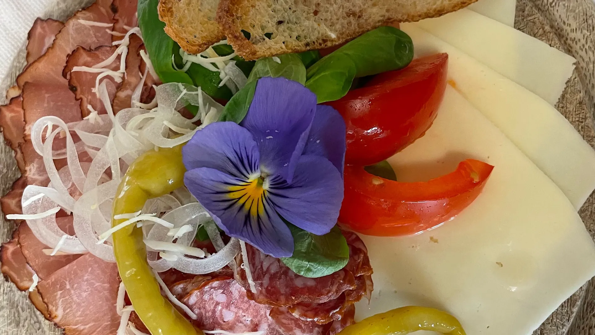 Gasthof Weisskugel: Bilder, die Sehnsucht wecken Wurst- und Käsescheiben mit Brot, Paprika, Tomaten und essbarer Blüte