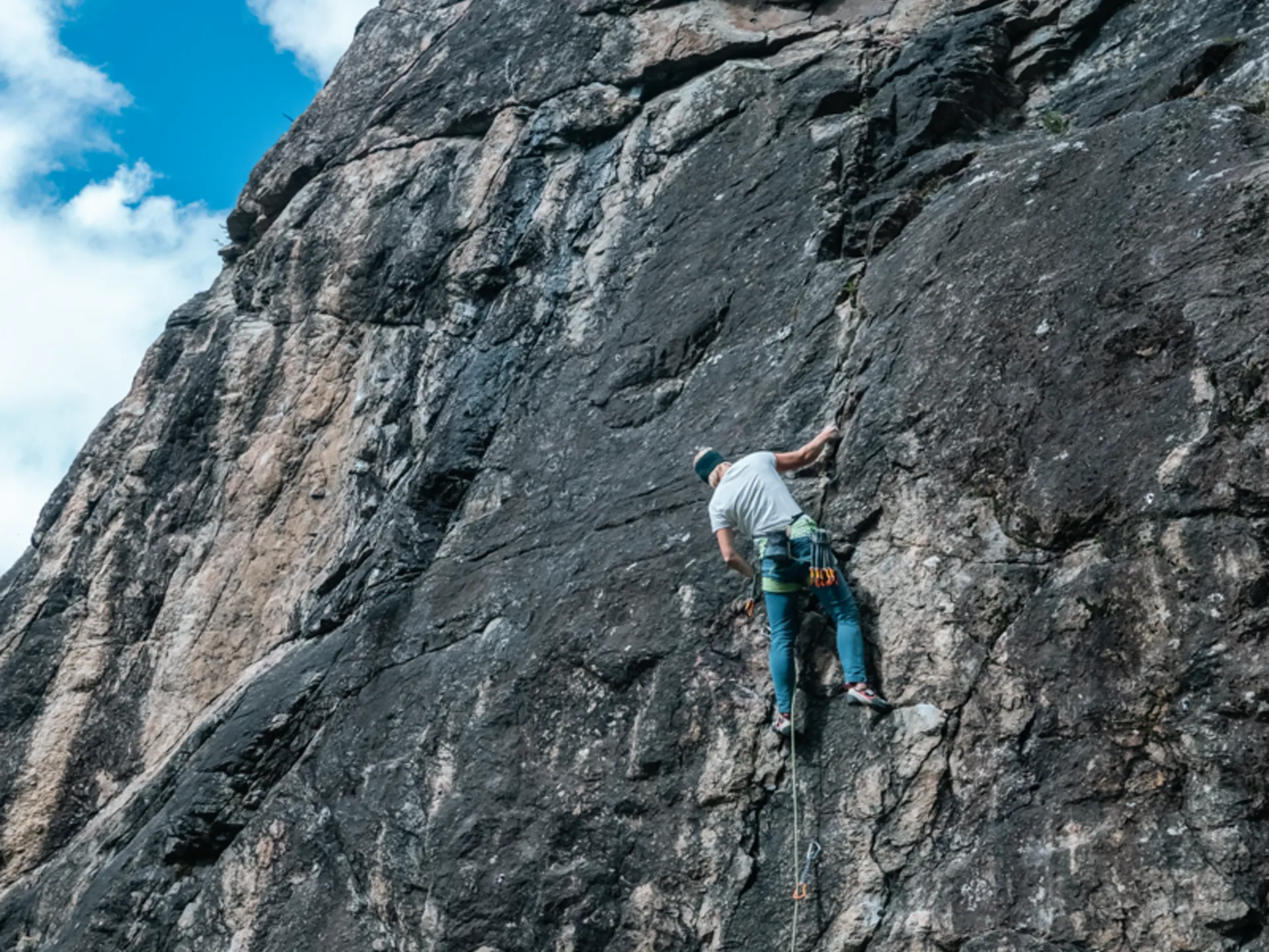 Climber on rock face secured by a person belaying below