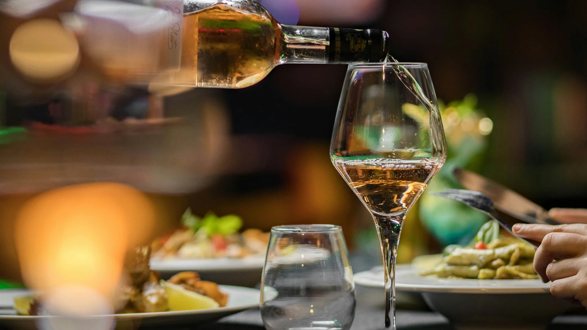 Wine being poured into a glass at a set restaurant table