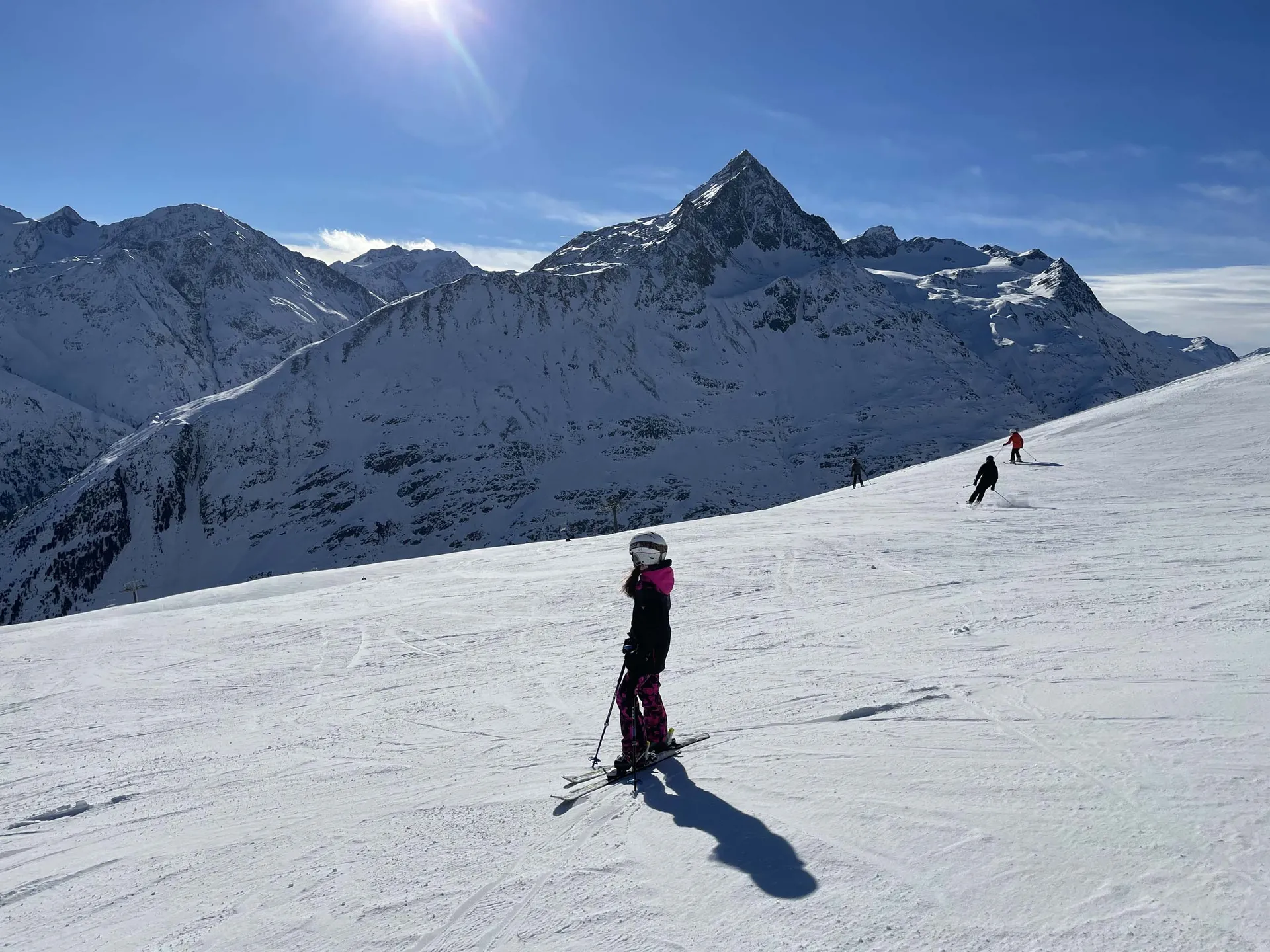 Skifahrerin auf sonniger Piste vor schneebedeckten Berggipfeln