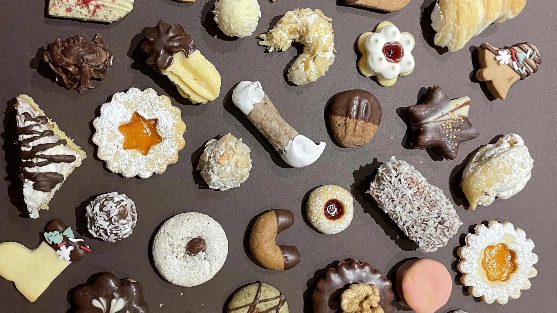 Gasthof Weisskugel: Bilder, die Sehnsucht wecken Bunt verzierte Weihnachtsplätzchen mit Schokolade, Puderzucker und Marmelade auf einem Tablett