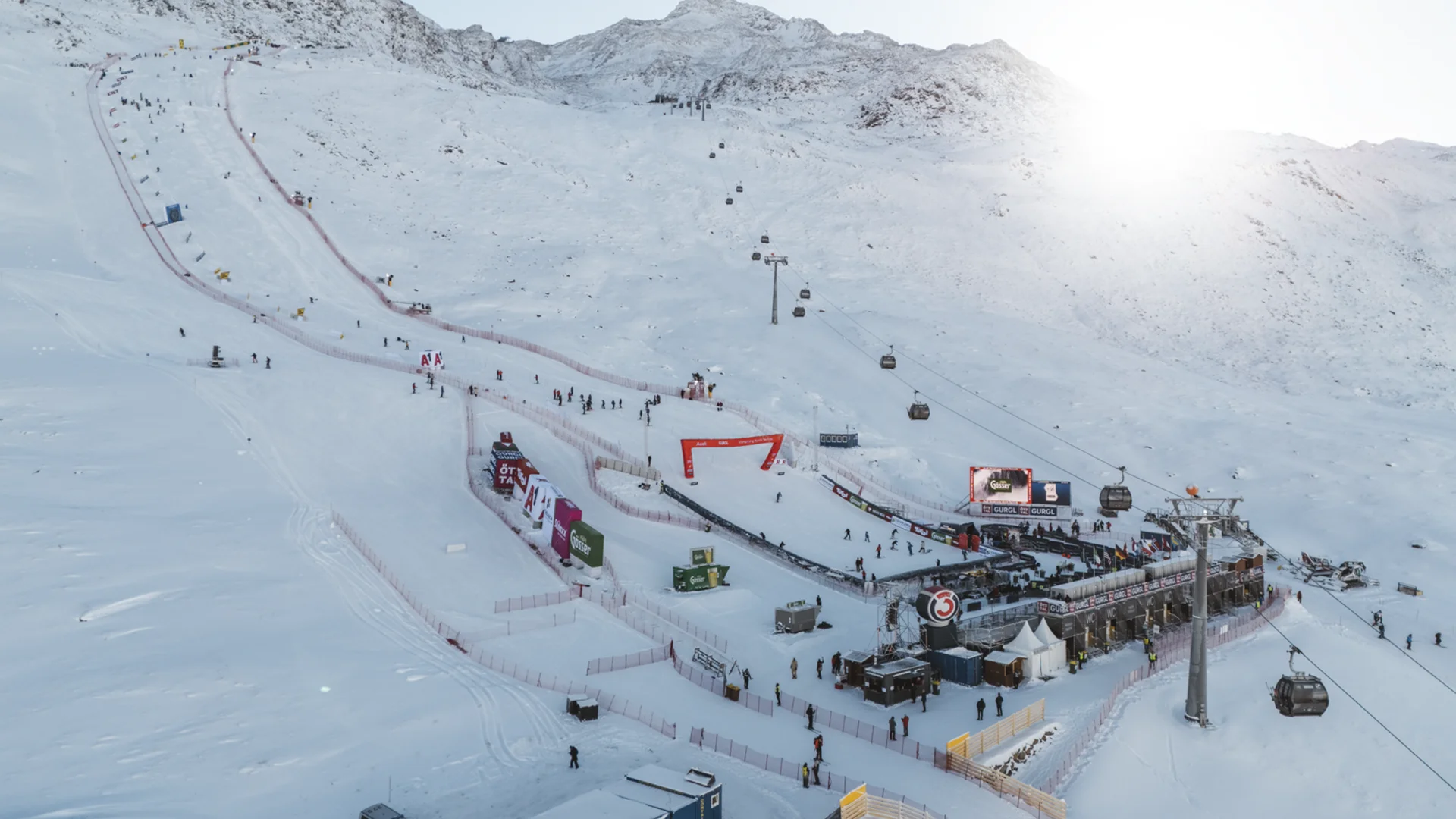 Skigelände mit Liften, Pisten und Zuschauern bei sonnigem Winterwetter
