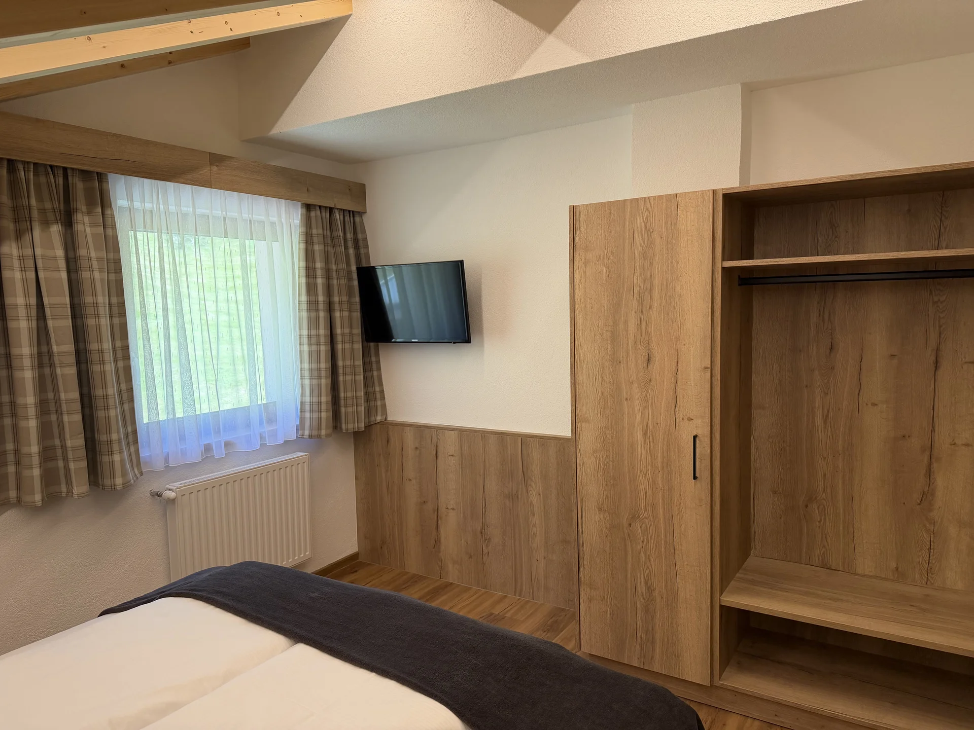 Weisskugel: your accommodation in Tyrol Bedroom with bed, television, window and open wooden wardrobe