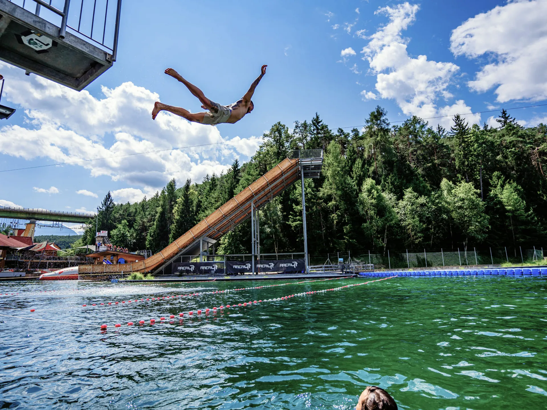 Man jumps from a water slide into a large swimming pool