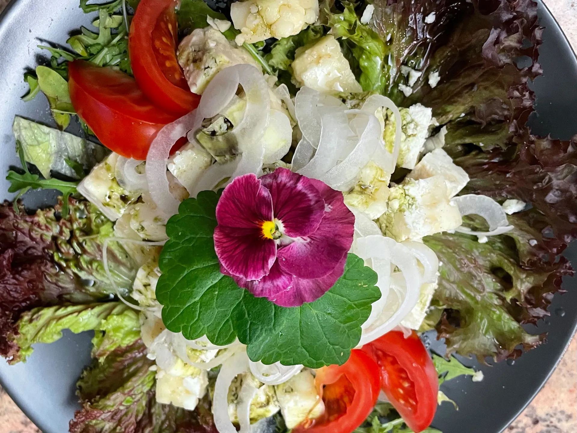 Gasthof Weisskugel: dein originales Restaurant in Vent Gemischter Salat mit Tomaten, Zwiebeln, Käse und einer violetten Blüte