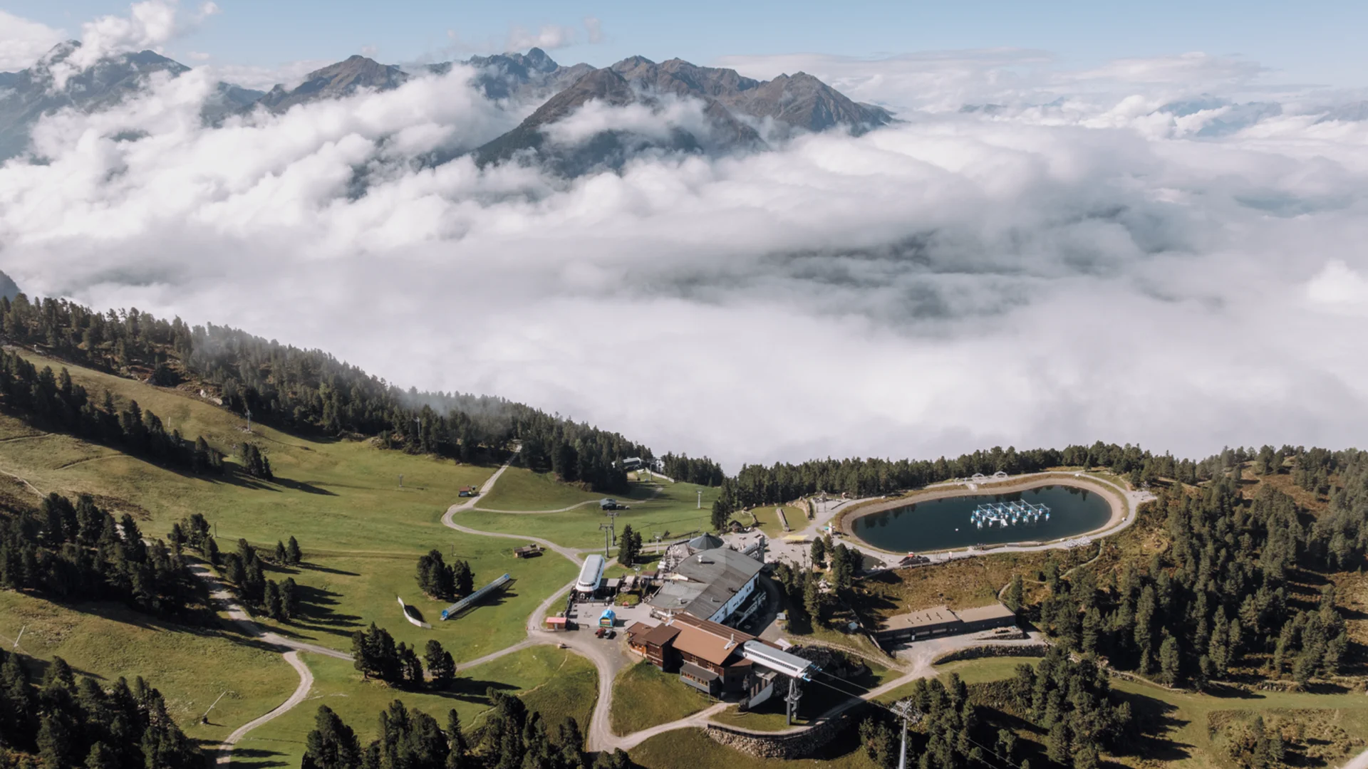 Berglandschaft mit See, Gebäuden und Wolken unter blauem Himmel