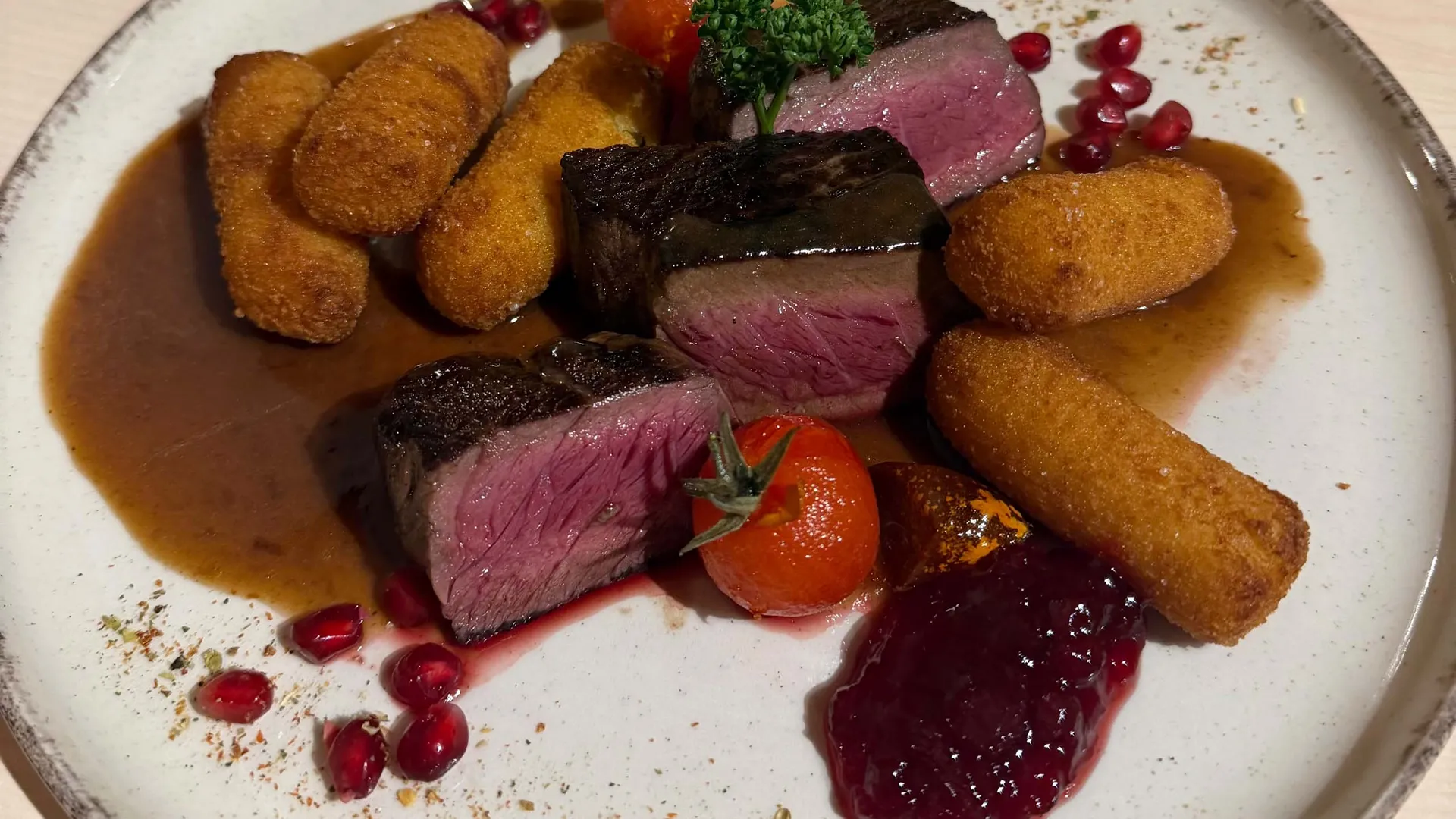 Gasthof Weisskugel: Bilder, die Sehnsucht wecken Gebratene Fleischstücke mit Kroketten, Sauce, Granatapfelkernen und Kräutern