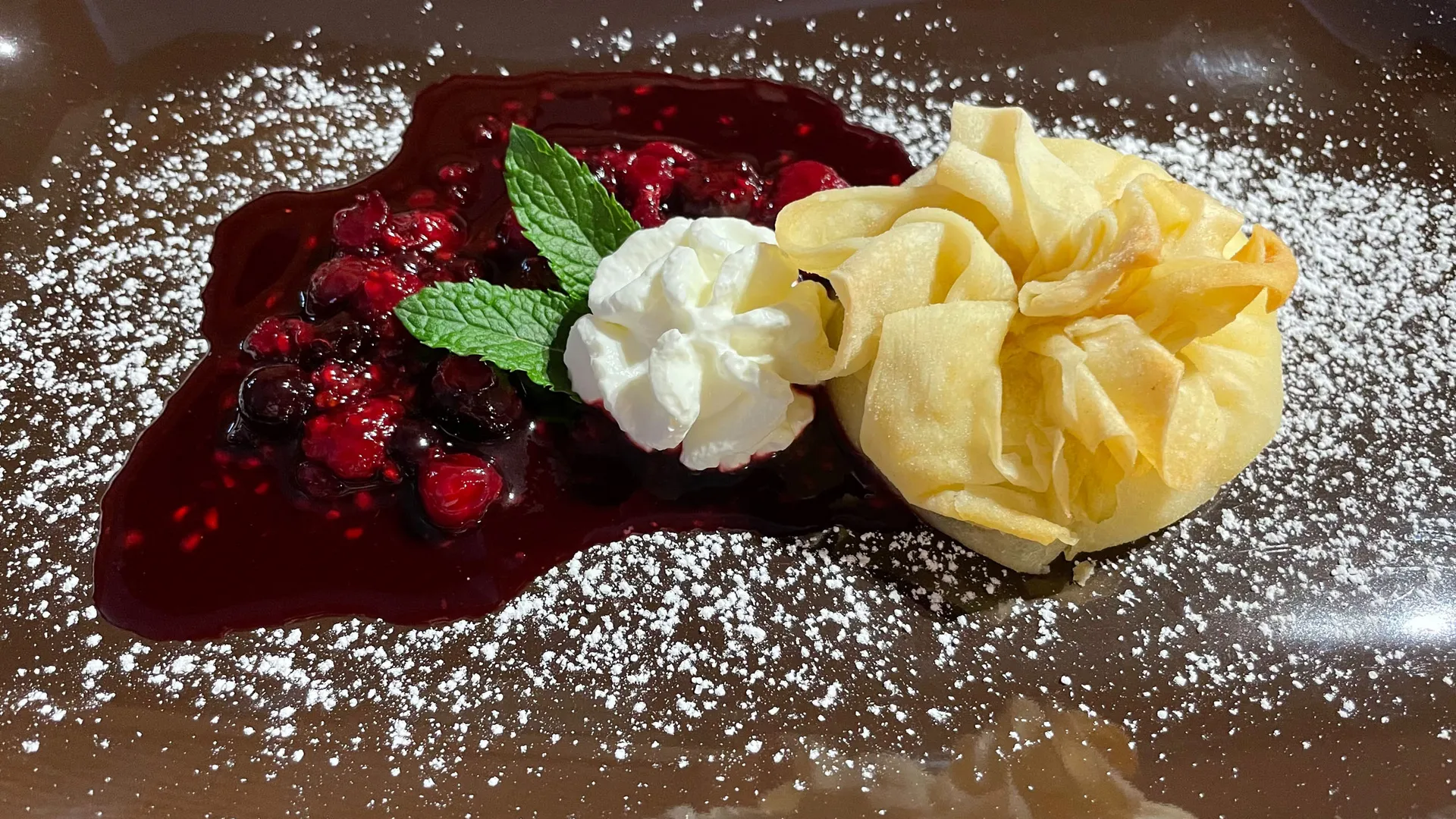 Gasthof Weisskugel: Bilder, die Sehnsucht wecken Dessert mit Beerenkompott, Sahne, Minze und knuspriger Teigblüte auf Teller