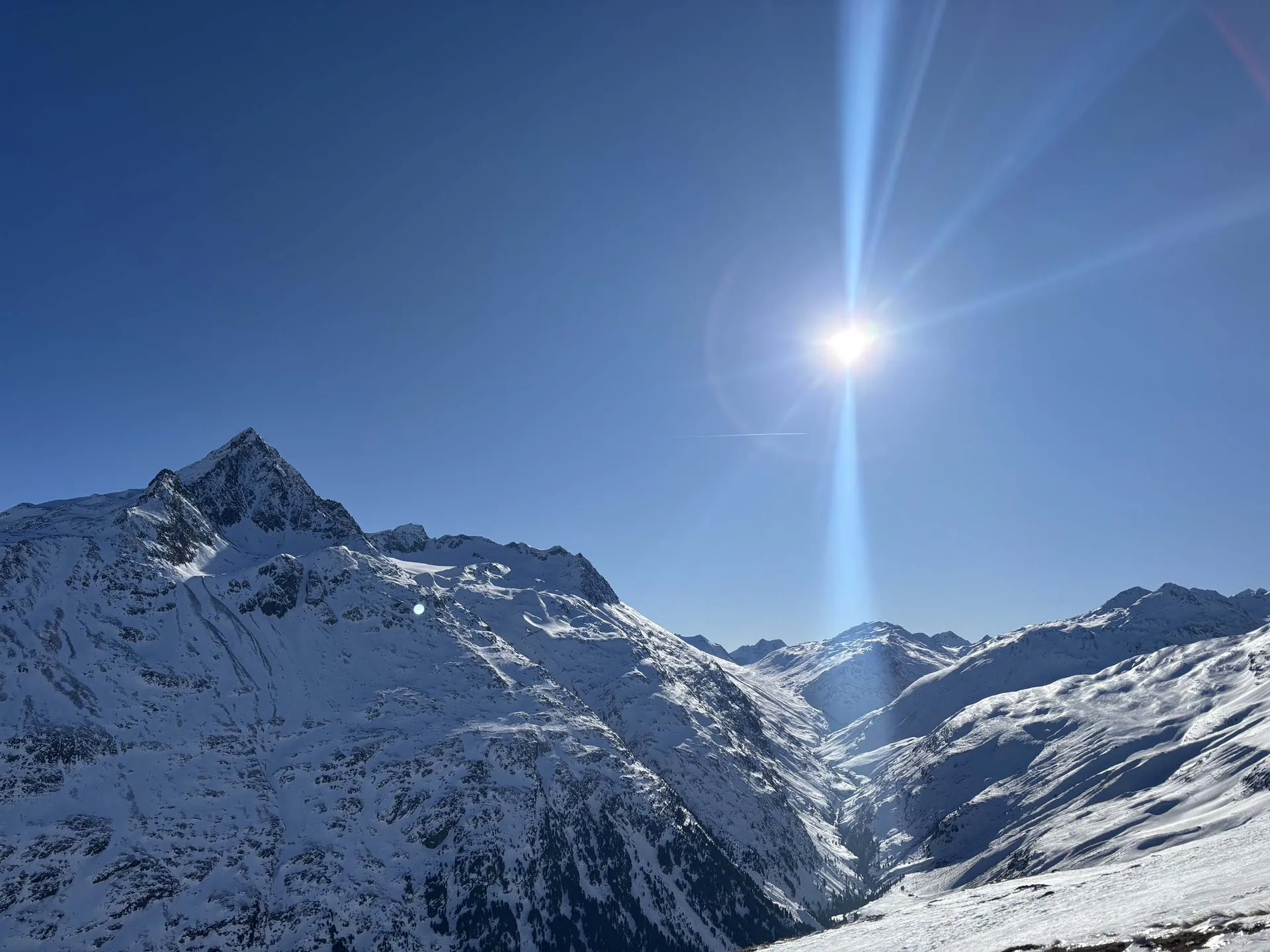 Verschneite Berggipfel und ein Tal unter strahlend blauem Himmel