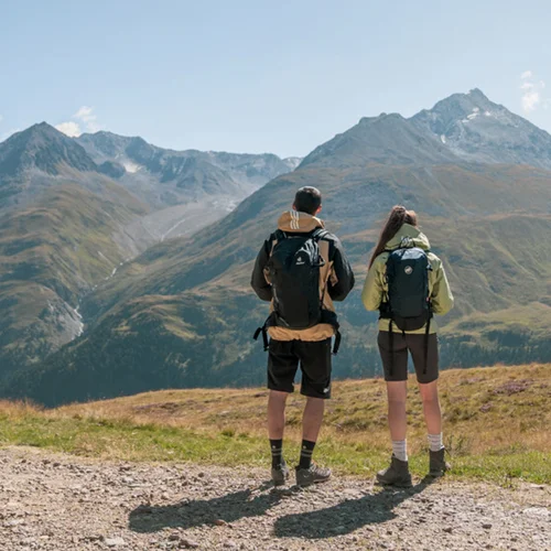 Zwei Wanderer mit Rucksäcken blicken auf Berglandschaft bei klarem Himmel