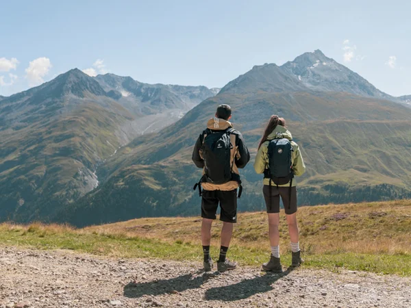 Zwei Wanderer mit Rucksäcken blicken auf Berglandschaft bei klarem Himmel
