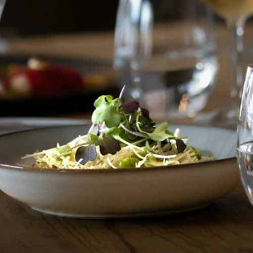 Gasthof Weisskugel in Vent: family-run since the beginning Plate of salad with sprouts and green leaves on a set dining table