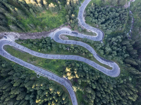 Luftaufnahme einer kurvigen Bergstraße mit Radfahrern und Wald