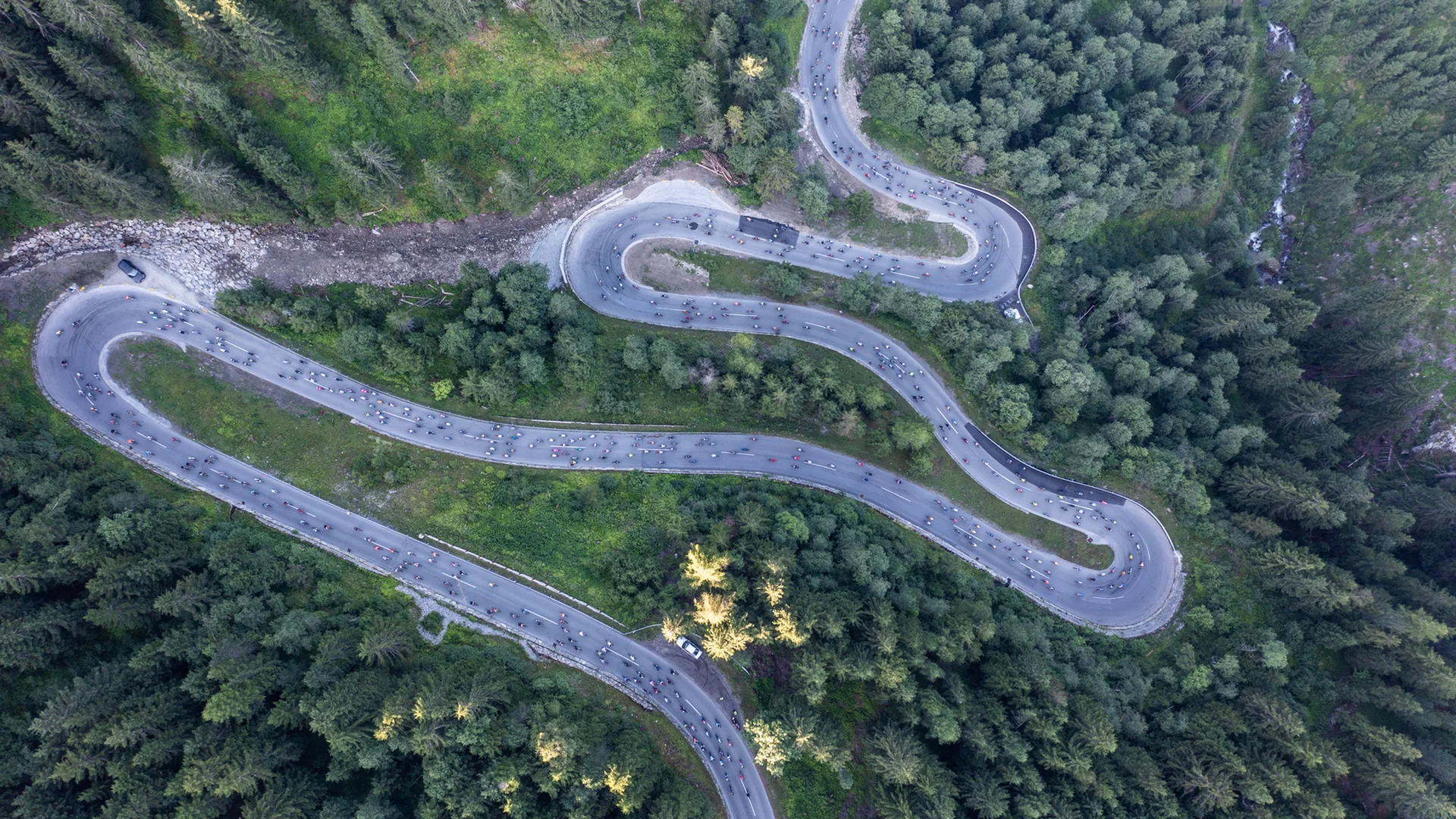 Luftaufnahme einer kurvigen Bergstraße mit Radfahrern und Wald