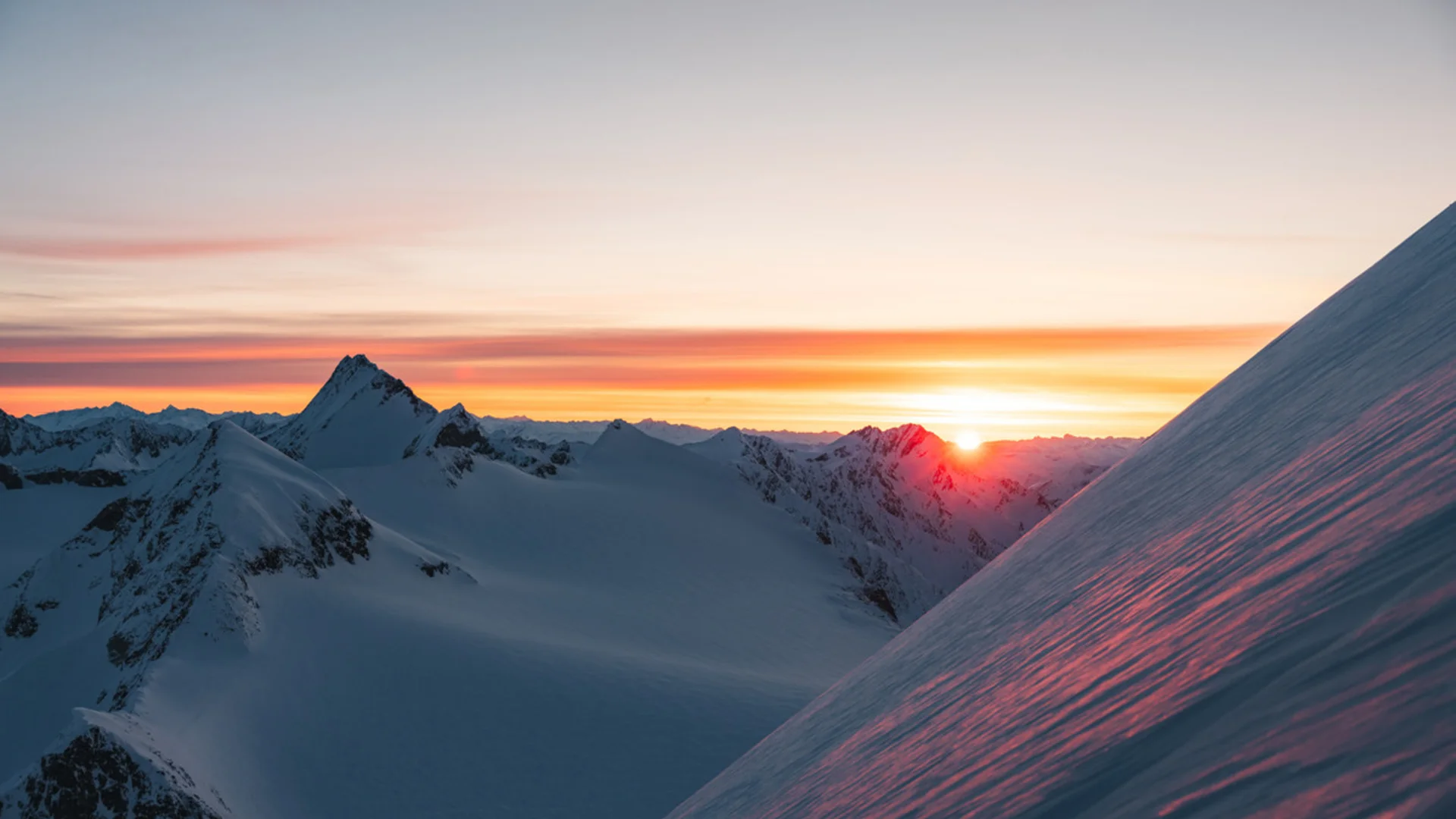 Sonnenaufgang über schneebedeckten Bergen mit farbigem Himmel