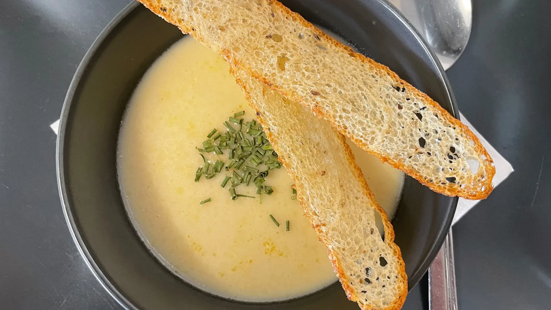 Gasthof Weisskugel: Bilder, die Sehnsucht wecken Cremige Suppe mit Schnittlauch und zwei gerösteten Brotscheiben in schwarzer Schale