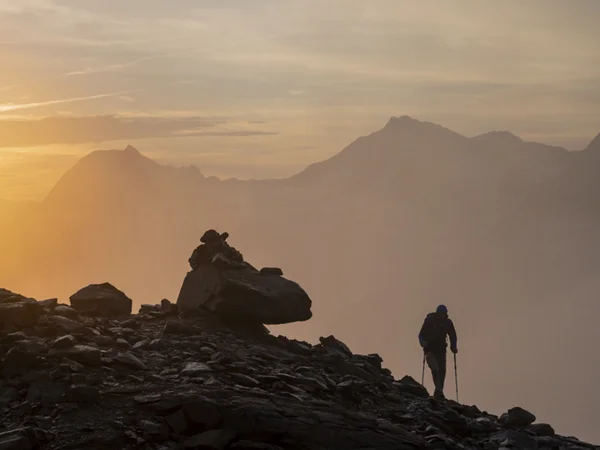 Gasthof Weisskugel in Vent: family-run since the beginning Wanderer auf felsigem Bergpfad bei Sonnenaufgang mit Nebel und Bergen