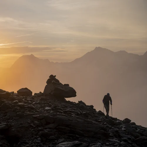 Gasthof Weisskugel in Vent: family-run since the beginning Wanderer auf felsigem Bergpfad bei Sonnenaufgang mit Nebel und Bergen