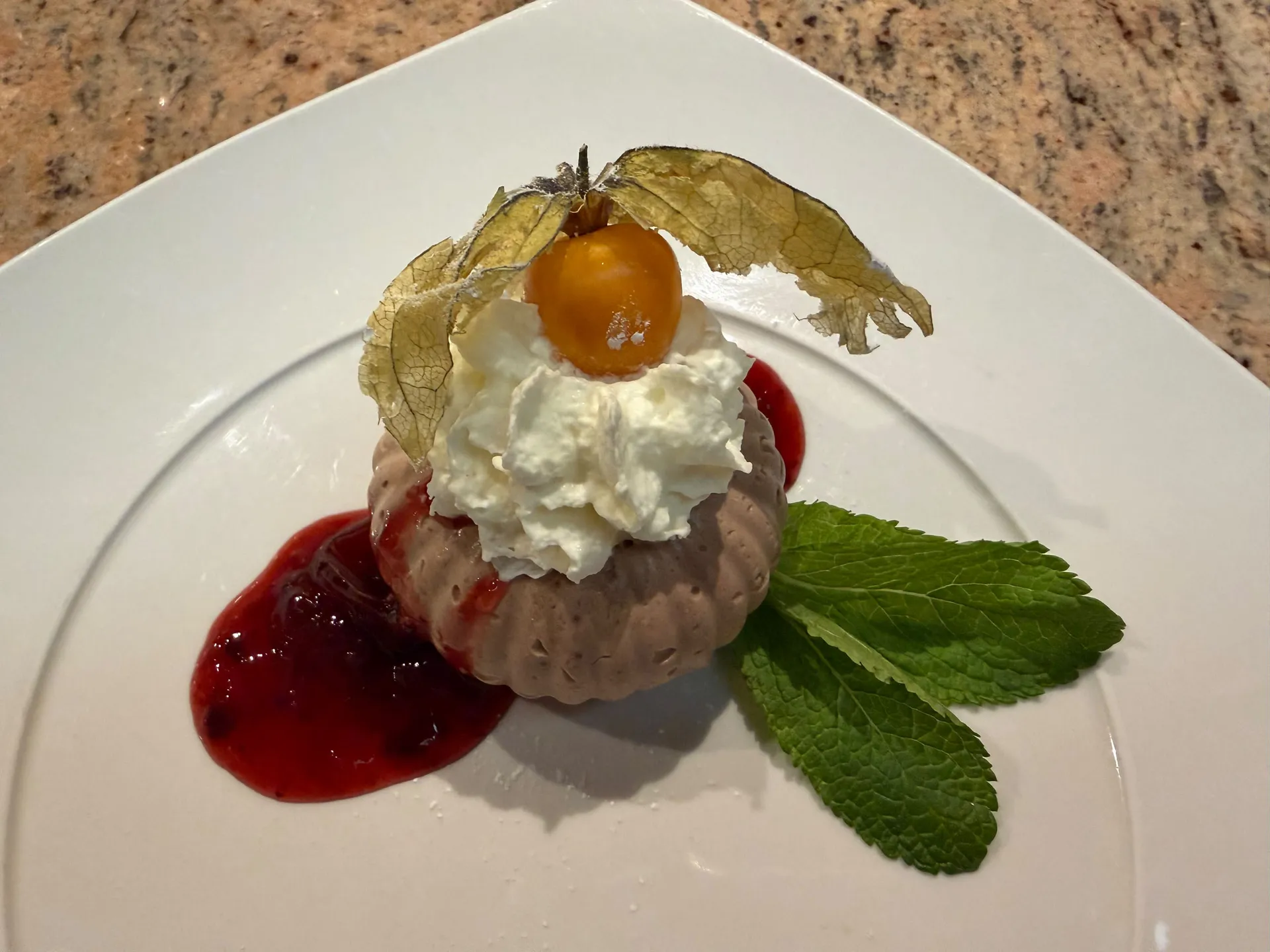 Gasthof Weisskugel: dein originales Restaurant in Vent Dessert mit Sahne, Physalis, Beerensoße und Minzblättern auf einem weißen Teller