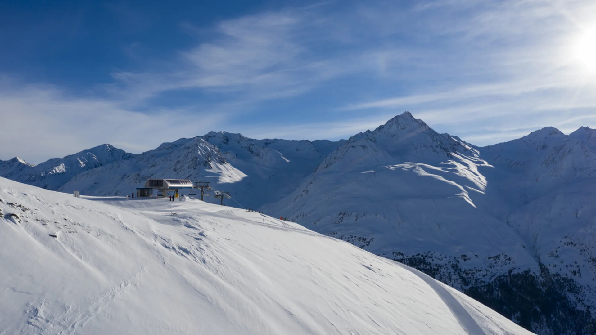 Schneebedeckte Berge mit Skiliftstation und blauem Himmel