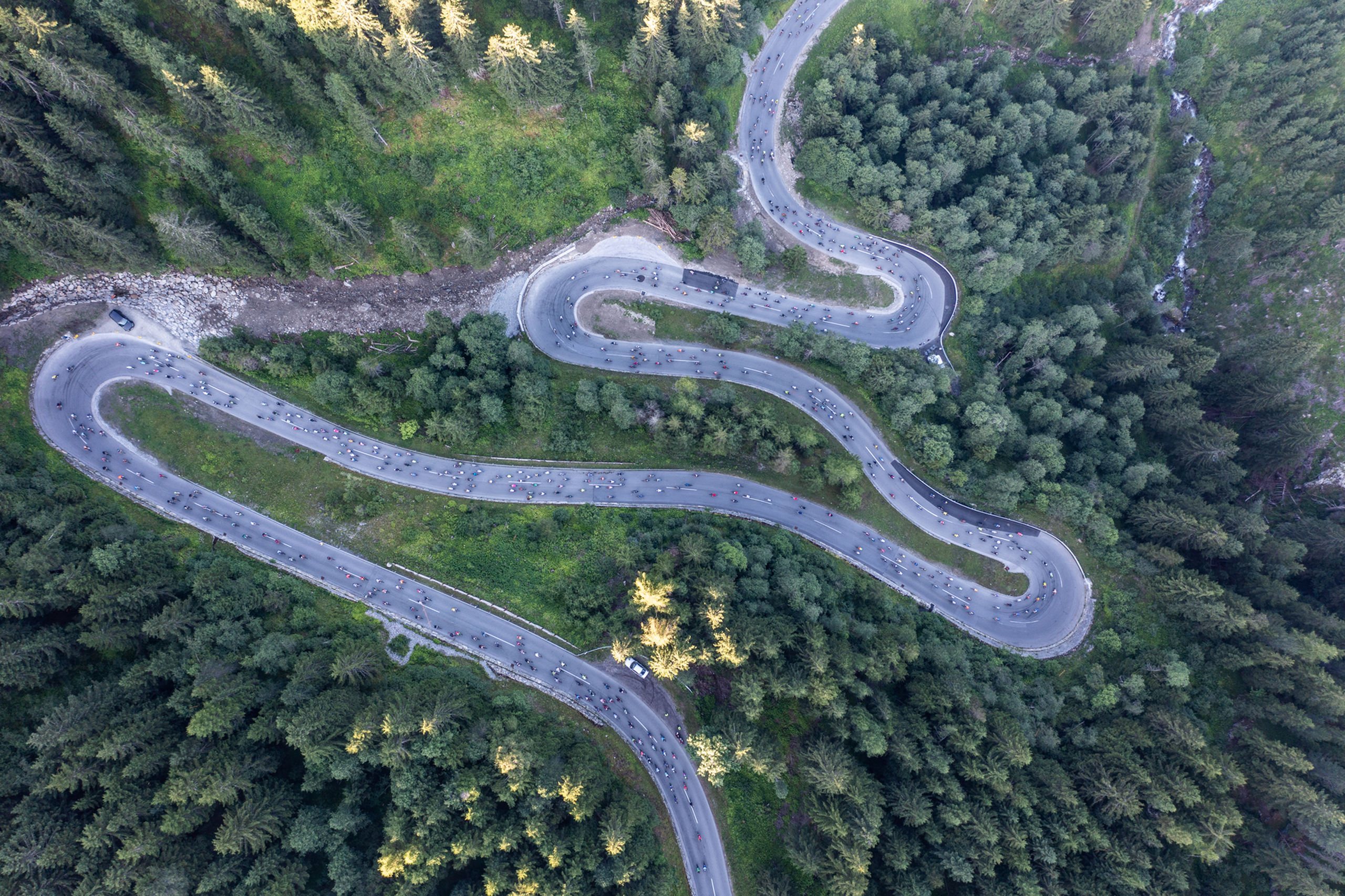 Luftaufnahme einer kurvigen Bergstraße mit Radfahrern und Wald
