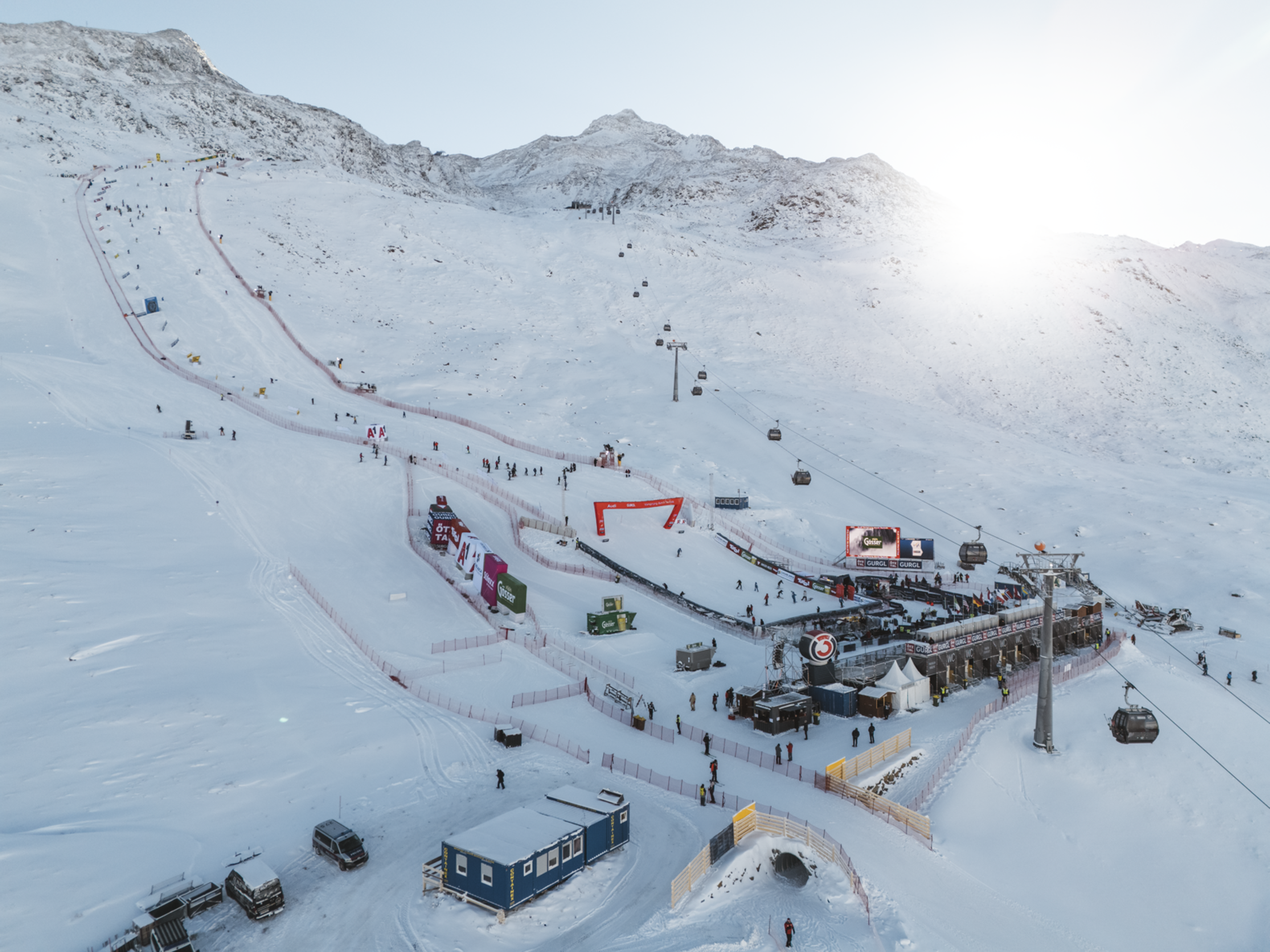 Skigelände mit Liften, Pisten und Zuschauern bei sonnigem Winterwetter