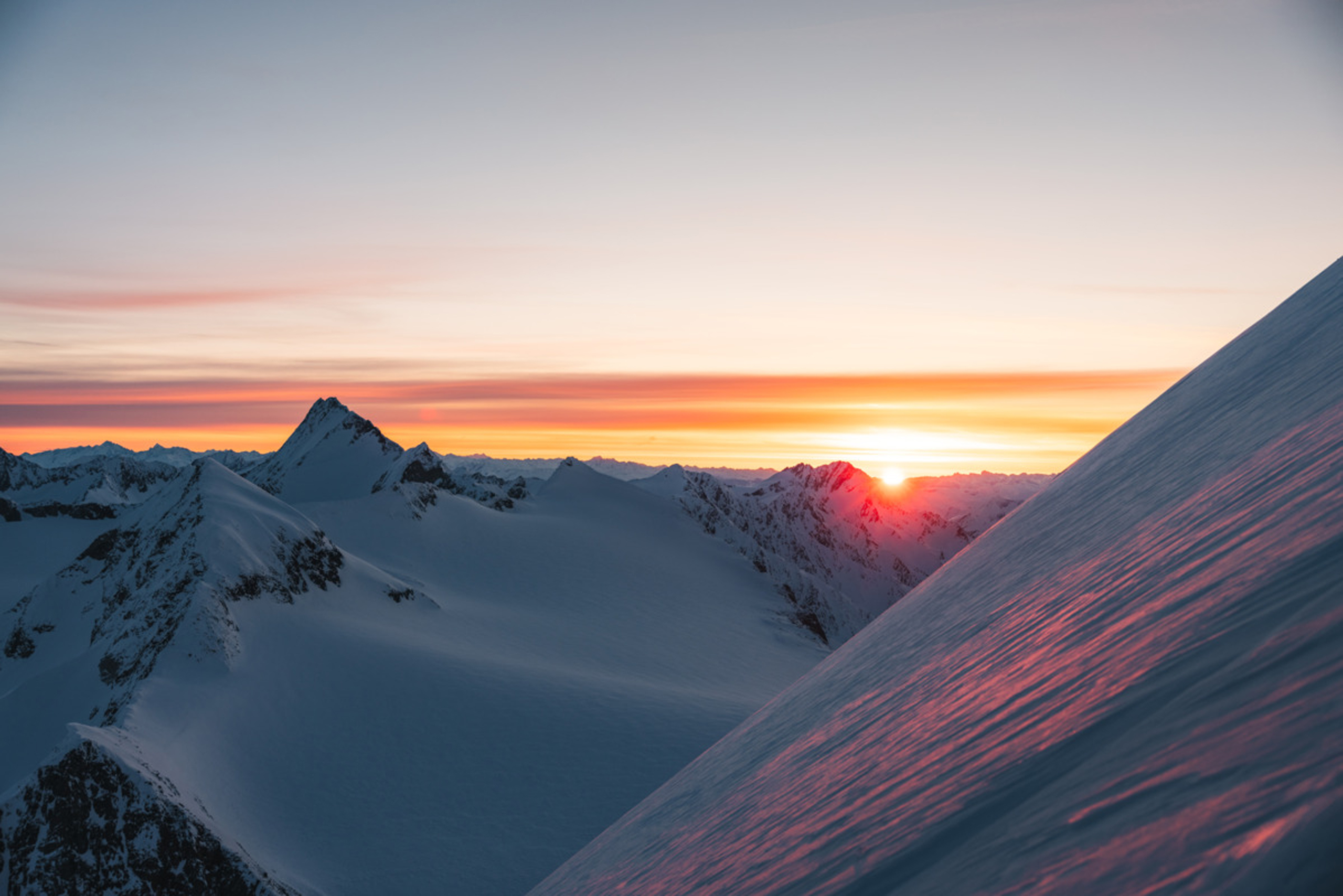 Sonnenaufgang über schneebedeckten Bergen mit farbigem Himmel