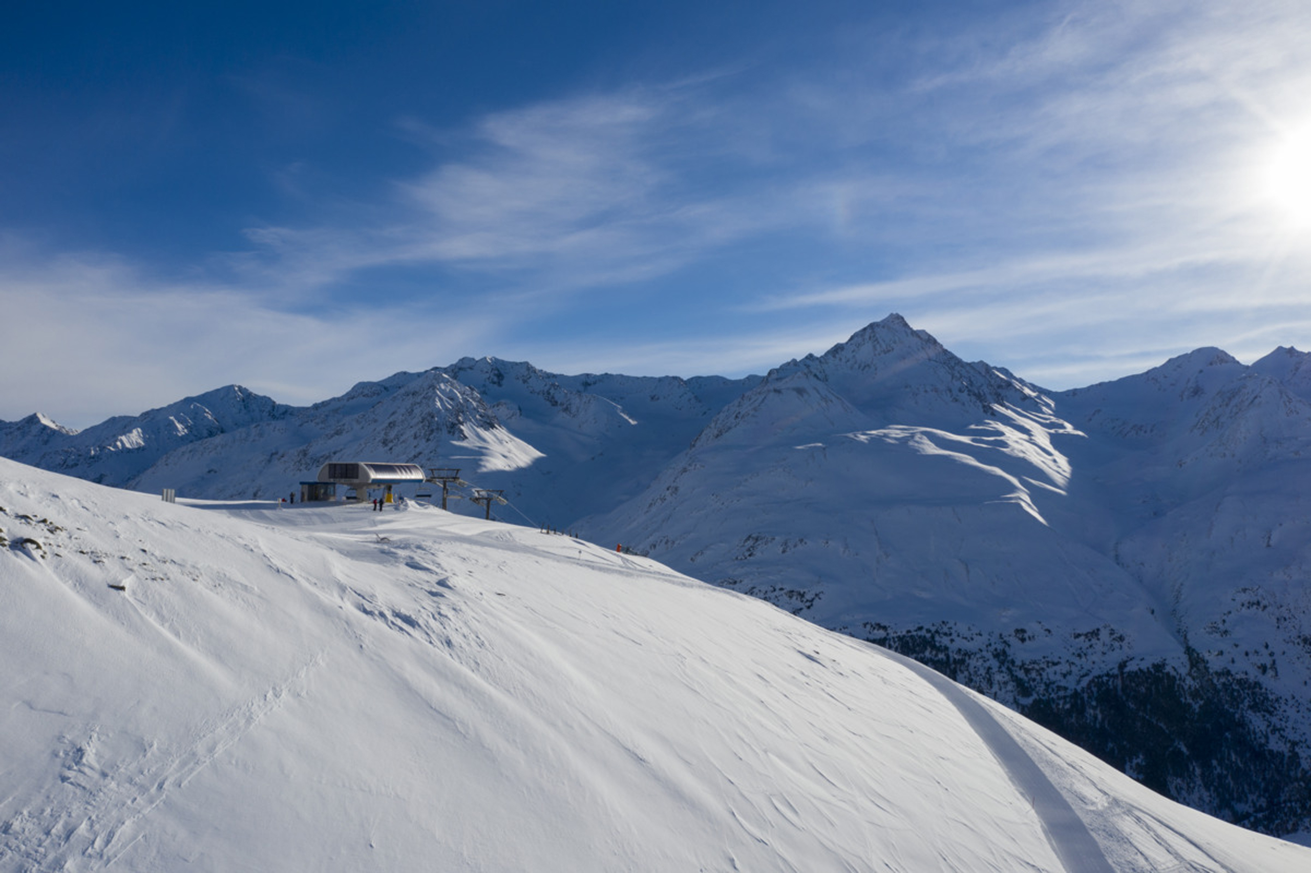 Schneebedeckte Berge mit Skiliftstation und blauem Himmel